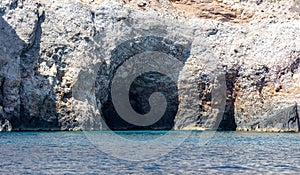 Cave and cliff, Aegean Sea. Cyclades Greece. Rock coast, turquoise water. Seascape near Ios island photo