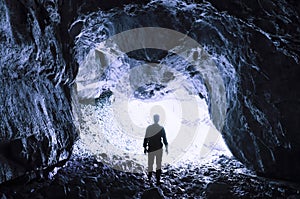 Cave entrance with man heading for the light photo
