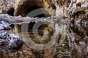 Cave entrance reflected in a clear river