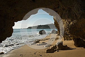 a cave entrance on a sandy beach overlooking the water's edge