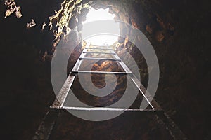 Cave hole with rustic ladder on wood and the light in out hole