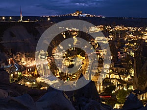 Cave houses and volcanic landscape of Cappadocian town Goreme and Uchisar castle at the horizon in the night