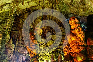 Cave rock formations are stalactites and stalagmites in colorful light. The miracle of the formation of stalagmites in the dark