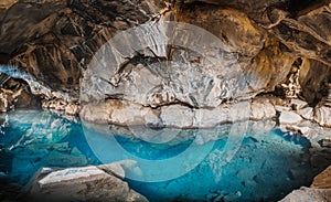 Cave Thingvellir and cavern Tingvelir in Iceland national park. Blue water and big rocks and stones inside.