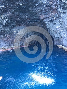 Cave and Waterfall in Napali Coast Mountains and Cliffs Seen from Pacific Ocean - Kauai Island, Hawaii.