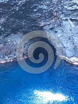 Cave and Waterfall in Napali Coast Mountains and Cliffs Seen from Pacific Ocean - Kauai Island, Hawaii.