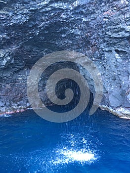 Cave and Waterfall in Napali Coast Mountains and Cliffs Seen from Pacific Ocean - Kauai Island, Hawaii.