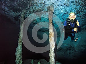 A Cavern Diver Poses Near Underwater Cave Columns