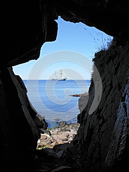 A cavern and a ship with white sails