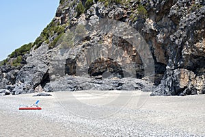 A cavernous cliff behind a sandy beach. Cove.