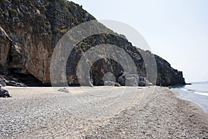 A cavernous cliff behind a sandy beach. Cove.