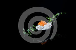 Caviar Seafood Appetizer garnished with green leaves, one spoon isolated on black background with reflections