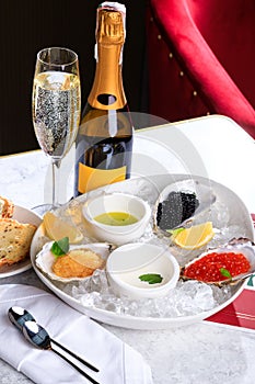 Caviar, sterlet caviar, pike caviar on white plate with ice. croutons. Bottle and glass of champagne. Sparkling wine