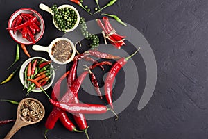 Cayenne pepper and fresh red chili and peppers with spices on a dark black background table in a rustic kitchen There is space for