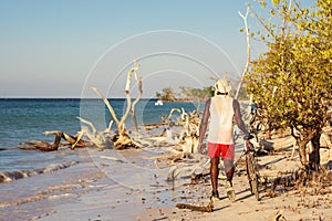 A Cuban-colored man walking alone at the beach with a bicycle in