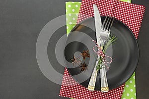 cChristmas place setting with ribbon. Black plate with fork and knife, decorated. Top view, copy space