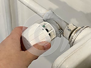 CClose up of a hand turning the thermostat radiator at coldest position. Heating of houses in the cold season