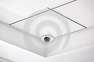 CCTV camera in the corner on a white suspended ceiling.