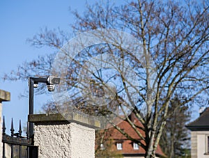 CCTV camera on the pole surveilling the area behind large cement fence