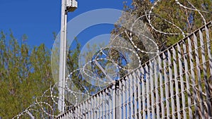 CCTV camera, razor wire, chain link fence surrounding a factory, Athens, Greece