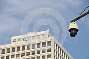 CCTV security camera with blue sky and white office building to monitor crimes and accidents 24 7 in the city center