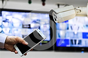 CCTV security camera monitor in office building and a businessman hand holding a smart phone.