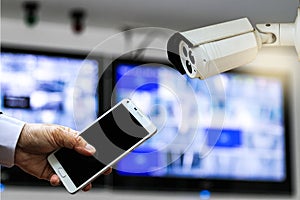 CCTV security camera monitor in office building and a businessman hand holding a smart phone.