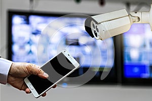 CCTV security camera monitor in office building and a businessman hand holding a smart phone.