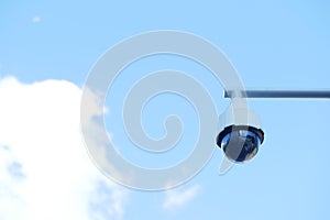 CCTV security camera operating against blue sky