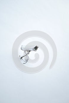 CCTV security camera operating on a white wall with copy space