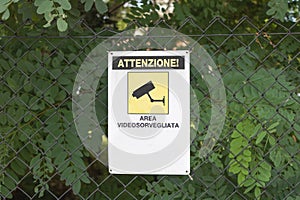 CCTV security camera sign on a chain link fence in a park