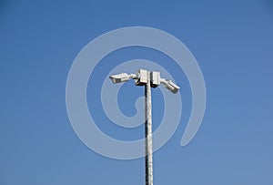 CCTV surveillance security camera on a black pole with blue sky background