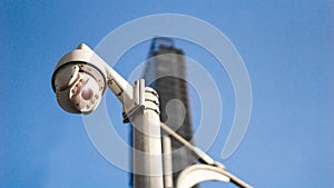 CCTV surveillance security camera on pole in city with tower building background for safety system area control outdoor and copy