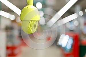 CCTV. Yellow surveillance camera on the background of the blurred trading floor of the store