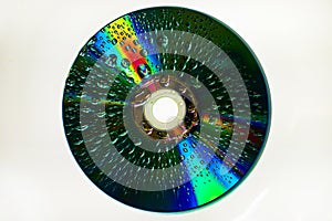 CD with brilliant beams of color and water drops on surface with white background