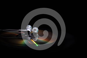 Cd compact disk and white headphones on a dark background. concept: listen to music