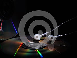 Cd compact disk and white headphones on a dark background. concept: listen to music