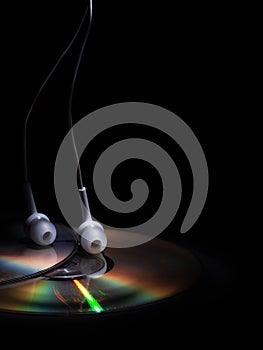 Cd compact disk and white headphones on a dark background. concept: listen to music
