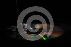 Cd compact disk and white headphones on a dark background. concept: listen to music