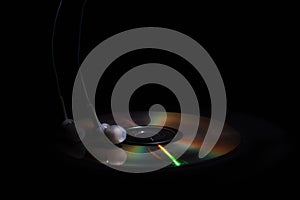 Cd compact disk and white headphones on a dark background. concept: listen to music