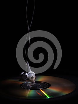 Cd compact disk and white headphones on a dark background. concept: listen to music