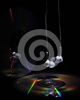 Cd compact disk and white headphones on a dark background. concept: listen to rap music
