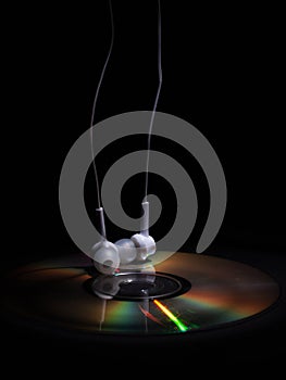 Cd compact disk and white headphones on a dark background. concept: relax music