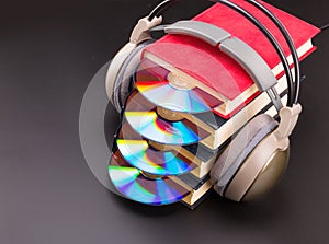 Cd sticks out from red books with headphones on it
