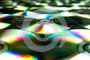 CDs / DVDs lying on a black background with colorful reflections of light.