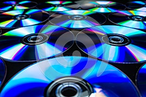 CDs / DVDs lying on a black background with colorful reflections of light.