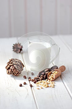 Cedar milk with pine nuts over white wooden table.