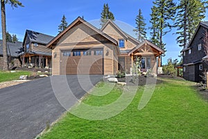 Cedar new house exterior with garage and driveway with green grass and pine trees