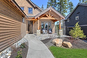 Cedar new house exterior with garage and driveway with green grass and pine trees