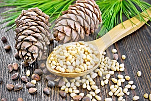 Cedar nuts peeled in spoon on wooden board